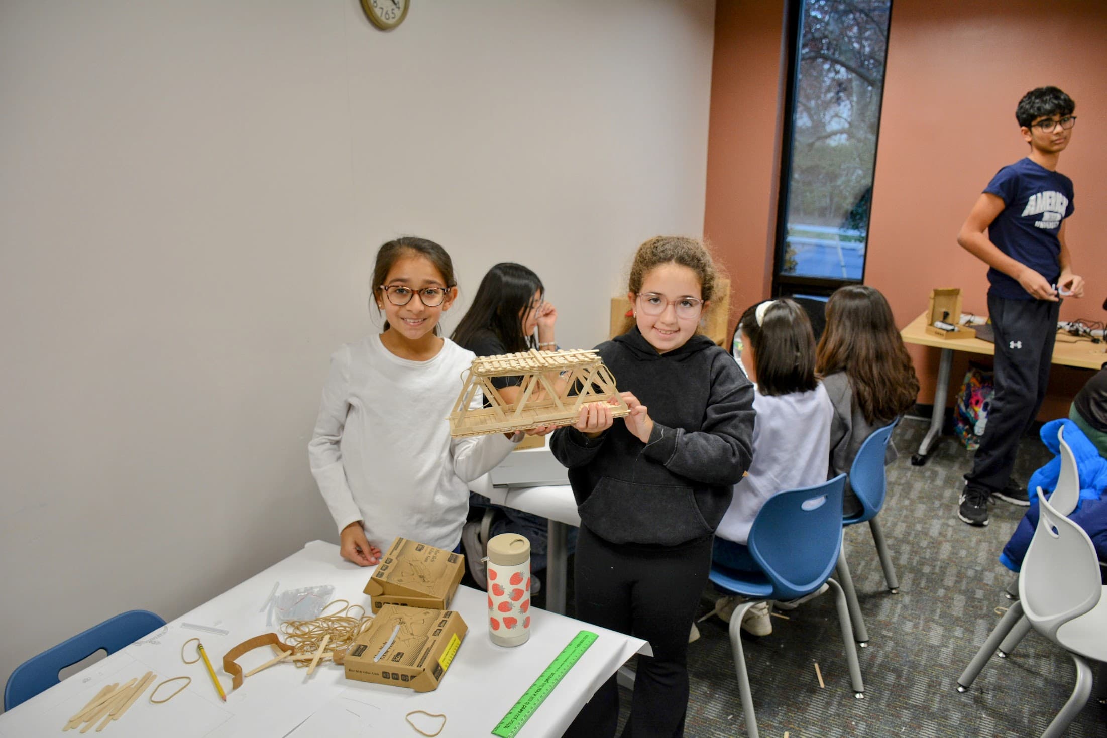 A popsicle stick bridge being constructed