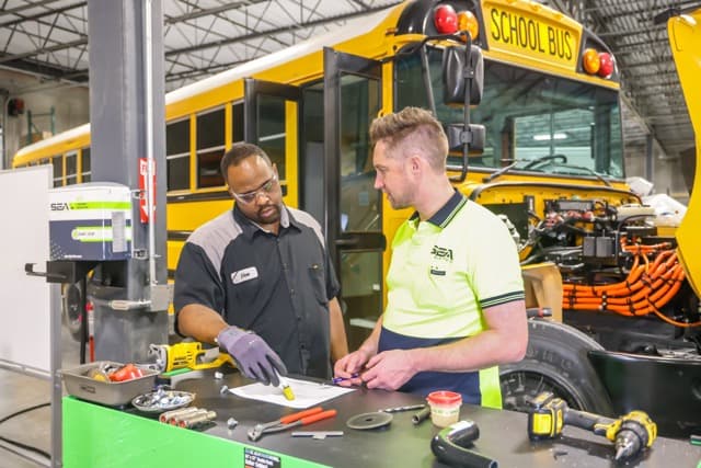 Un autobús escolar amarillo que muestra su color de seguridad distintivo, espejos grandes y señalización de salida de emergencia