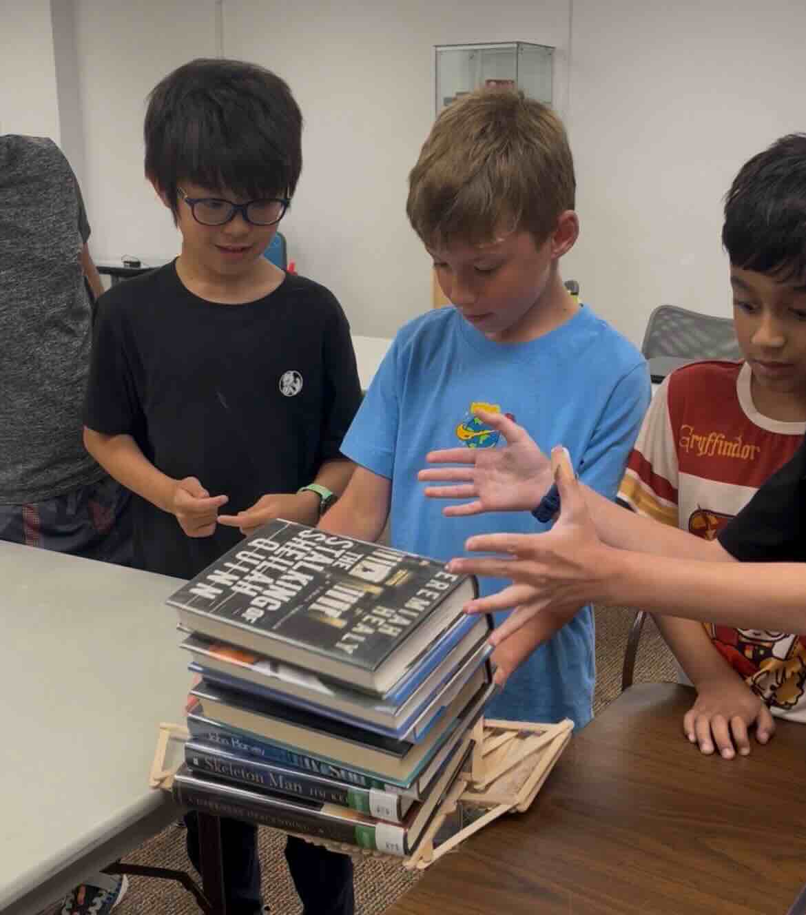 Students testing a failed bridge with books during an Avanza STEM engineering workshop