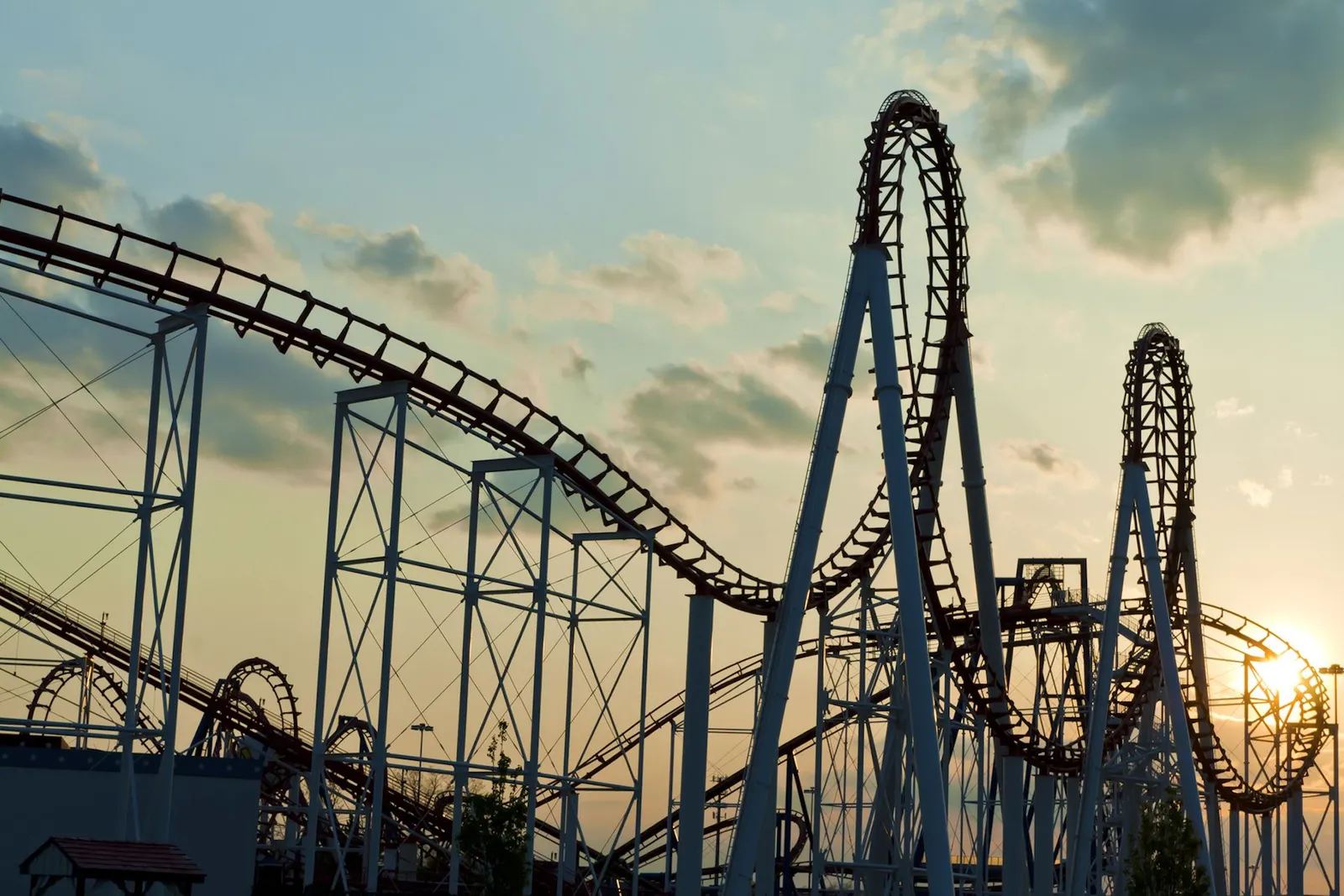 A roller coaster with steep drops and loop-the-loops against a bright sky, showing the track design that keeps riders safely on board