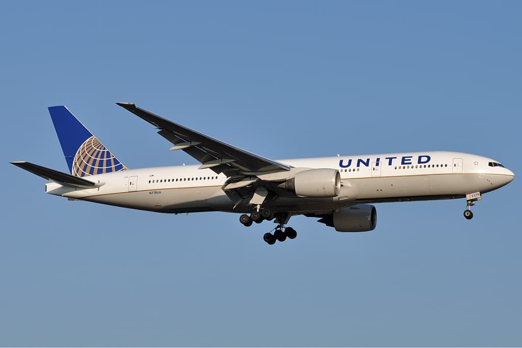 A United Airlines Boeing 777-200 in flight, with its curved airfoil wings and upturned winglets clearly visible