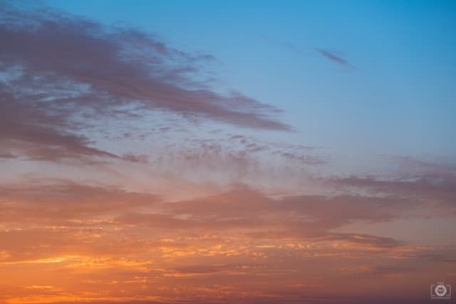 Un cielo que transita del azul profundo en la parte superior a tonos cálidos anaranjados y rosados cerca del horizonte al atardecer