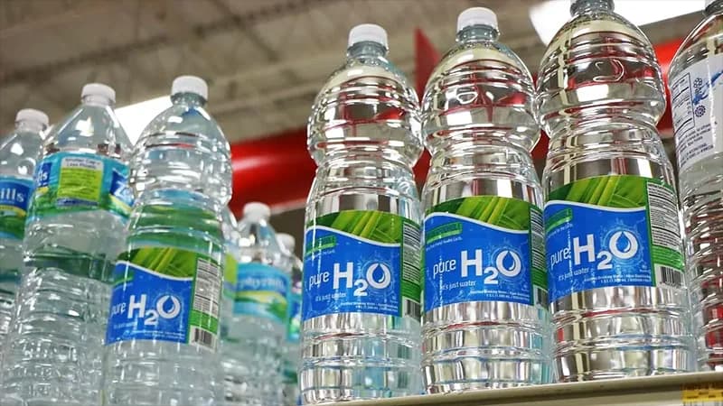 A clear plastic water bottle showing its ridged sides, threaded neck, and structural base design
