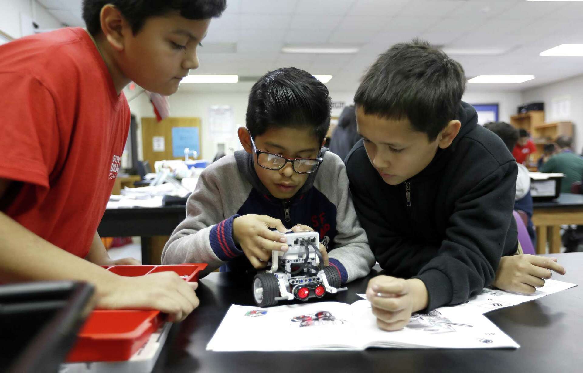 Tres estudiantes trabajando juntos para construir y programar un robot LEGO